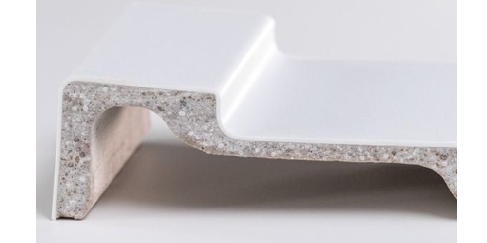 Close-up of white speckled L-shaped shower tray base with seamless design and smooth finish on plain background