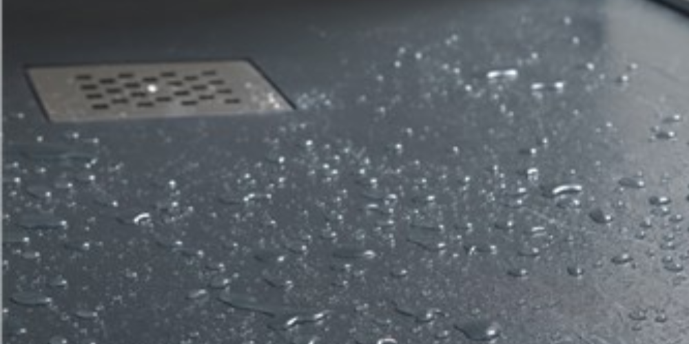 Wet shower floor with water droplets and square metal drain, creating a clean, fresh bathroom ambiance