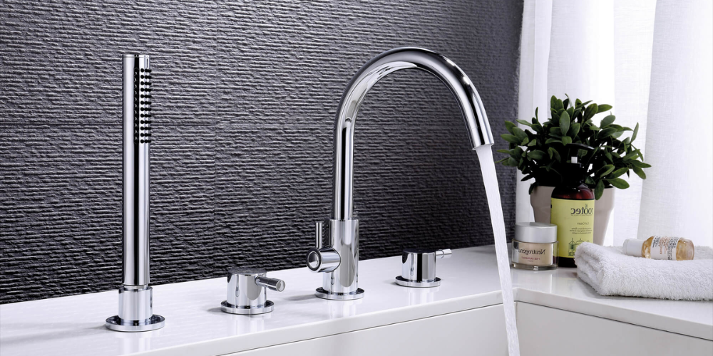 Chrome 4-hole bath tap with flowing water on white countertop, accompanied by plant and toiletries.