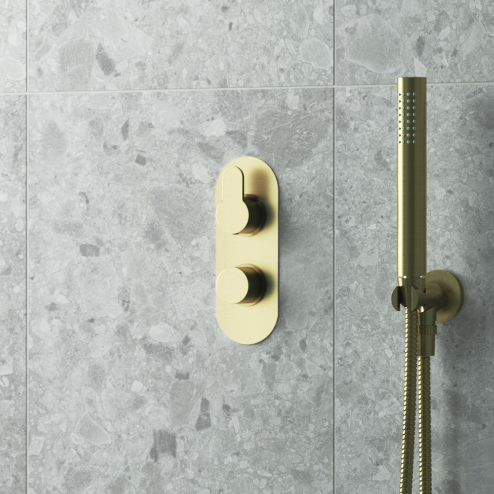 Shower with textured grey tile wall, brass knobs, and matching handheld showerhead for luxurious feel.