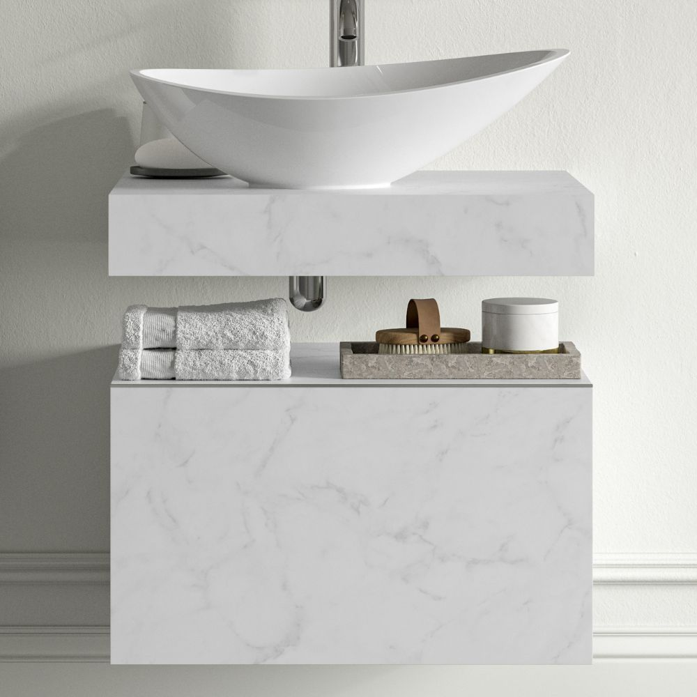 Marble-finish bathroom vanity with vessel sink, folded towel, and tray with toiletries.
