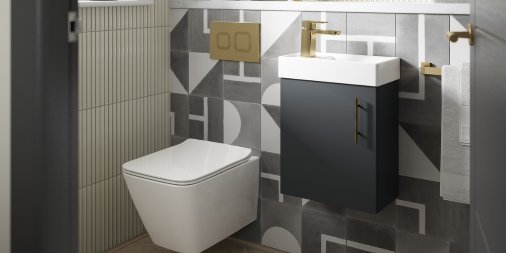 Bathroom with geometric grey tiles, wall-mounted white toilet, sleek sink, and gold fixtures in minimalist design.